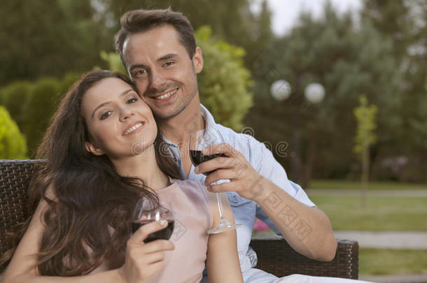 一对快乐的年轻夫妇在公园里喝红酒的画像