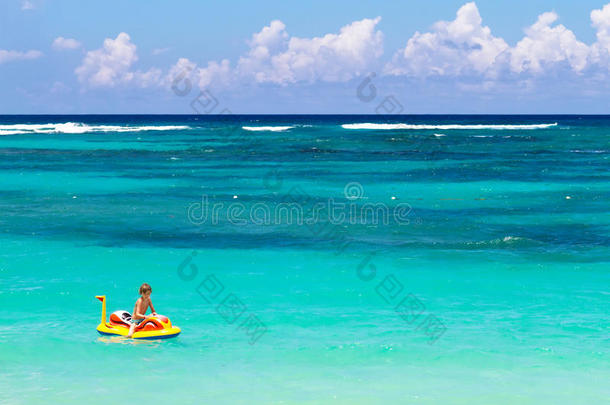 热带海滩上的充气船上的小男孩