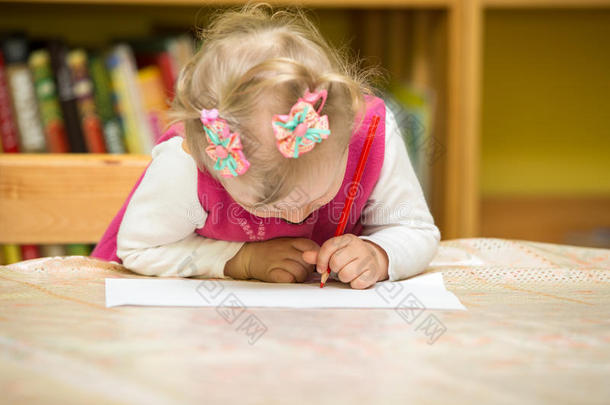 幼儿园的小女孩在桌边用彩色铅笔画画。幼儿园小女孩画画