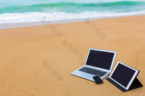 夏日海滩上的笔记本电脑、平板电脑和智能手机