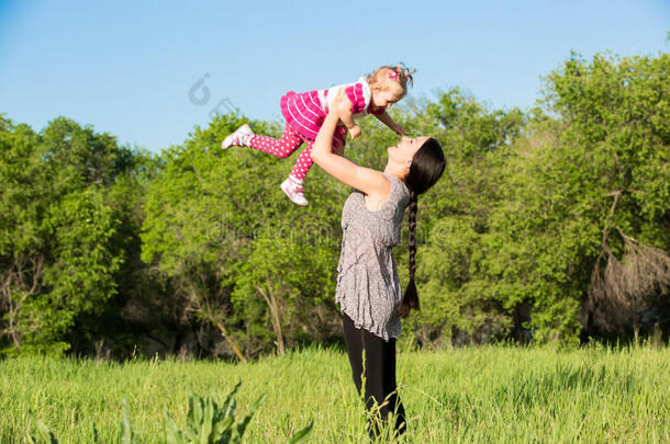 快乐的妈妈和小女孩拥抱大自然童年和家庭的概念