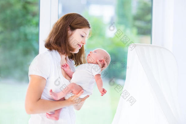 漂亮的年轻妈妈和她刚<strong>出生</strong>的<strong>宝宝</strong>在一个大窗户前