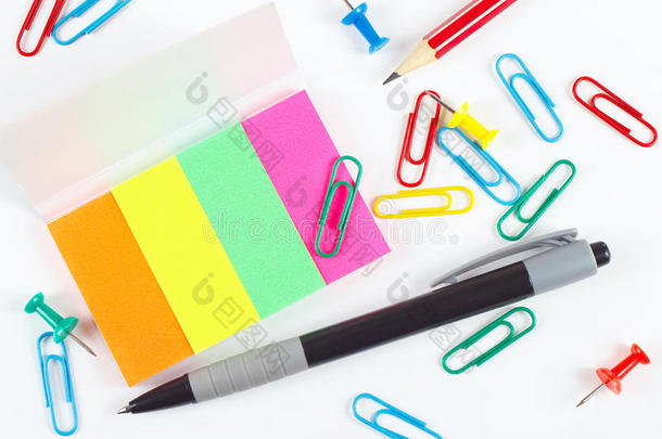 <strong>白色桌面上</strong>有钢笔、铅笔、回形针、图钉和彩色贴纸