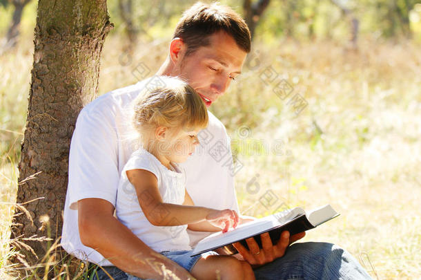 年轻的父亲和他的小女儿读圣经