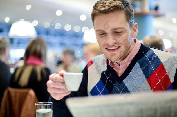 微笑的男人在餐馆看报纸