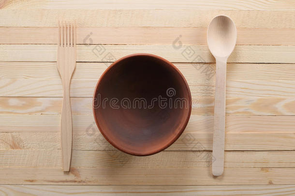 木制的勺子和叉子放在木板上的泥碗上