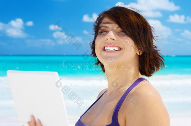 海滩上拿着笔记本电脑的女人