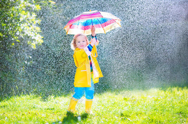 可爱的蹒跚学步的孩子在雨中打伞