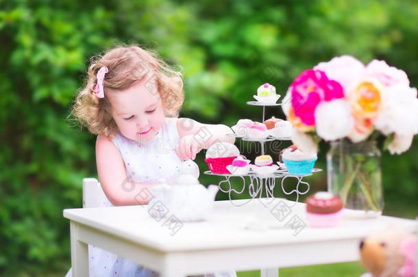 卷曲可爱的蹒跚学步的女孩玩着玩偶的茶话会