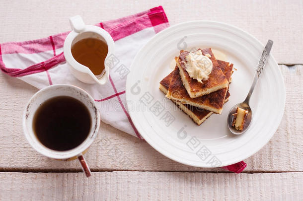 一块砂锅菜放在一个圆盘子里，一杯奶油，一杯咖啡，倒蜂蜜