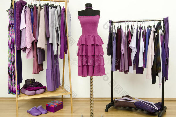 衣架上有紫色衣服的衣柜，模特身上有一件连衣裙。