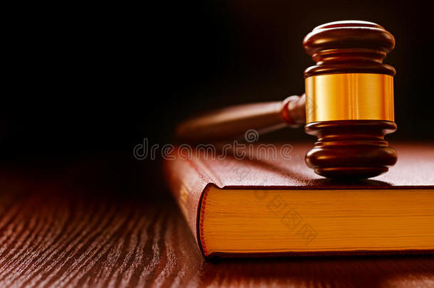 木头和黄铜的法官在法律书上敲木槌