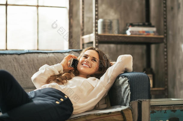 快乐的女人躺在沙发上打手机