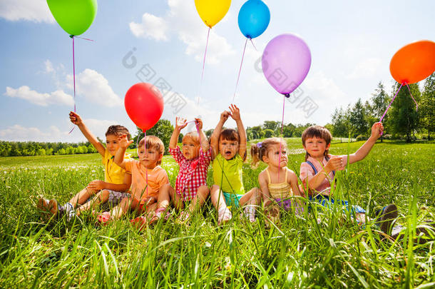 坐在空中拿着气球的有趣的孩子们