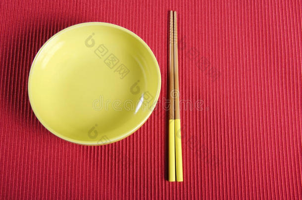 黄色的筷子和碗放在红色的桌子上放置垫子。