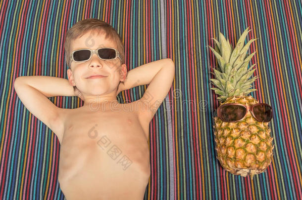 快乐的孩子和菠萝在毛巾上晒太阳