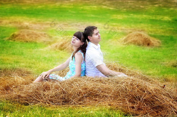 一对幸福的情侣在干草堆上的田野里玩得开心。夏天