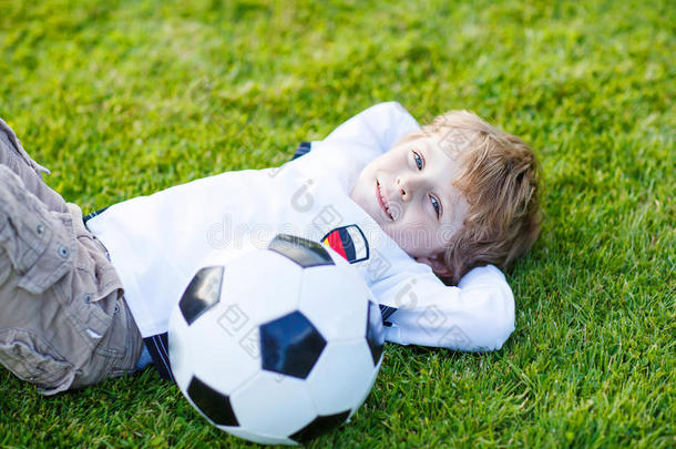 四岁的金发男孩在足球场上踢球休息