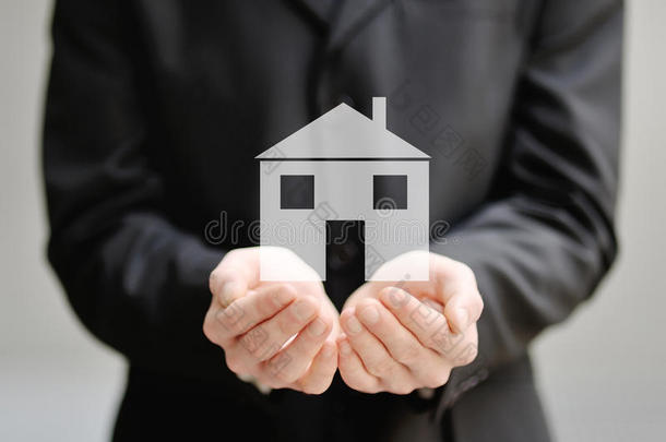 一个男人的手拿着房子保险和保护的概念