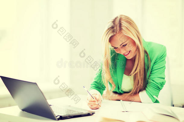微笑的女学生在笔记本上写字