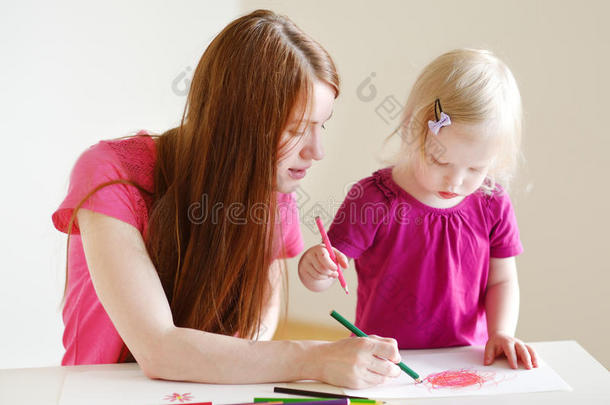 蹒跚学步的女孩和妈妈用铅笔画画