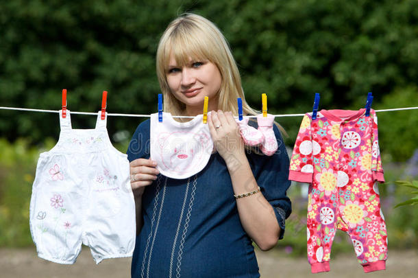 孕妇穿着婴儿衣服。晾衣绳上的婴儿衣服。