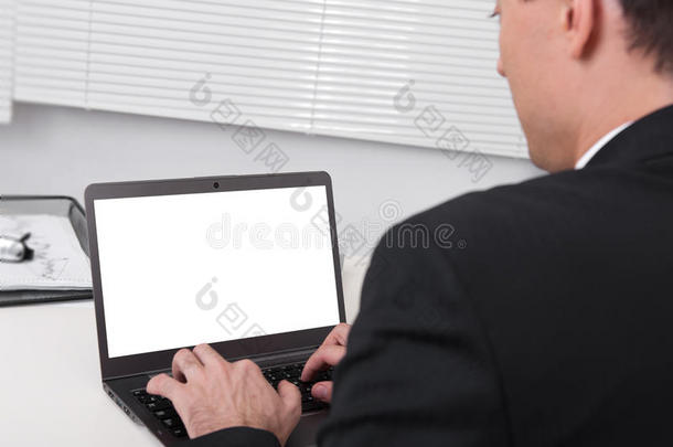 <strong>商务</strong>人士在办公桌上忙着使用<strong>笔记本</strong>电脑的后视图