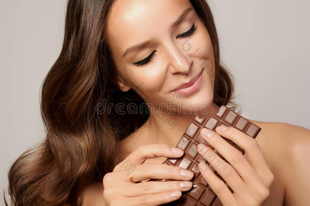 一个年轻的女孩抱着一头漂亮的黑头发，享受着巧克力的<strong>滋味</strong>