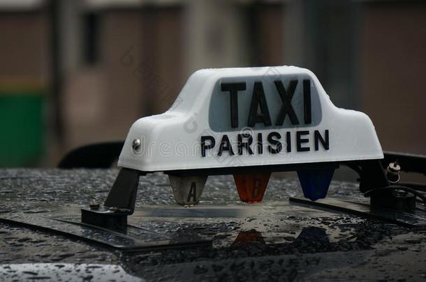 雨落在一辆黑色的巴黎出租车上，上面有白色的巴黎出租车标志