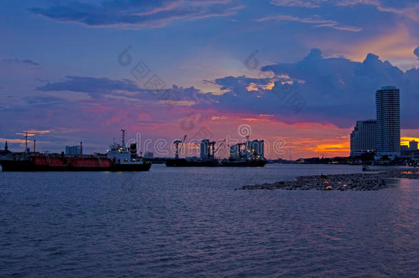 江边夕阳的天空上，载着货物的工业船
