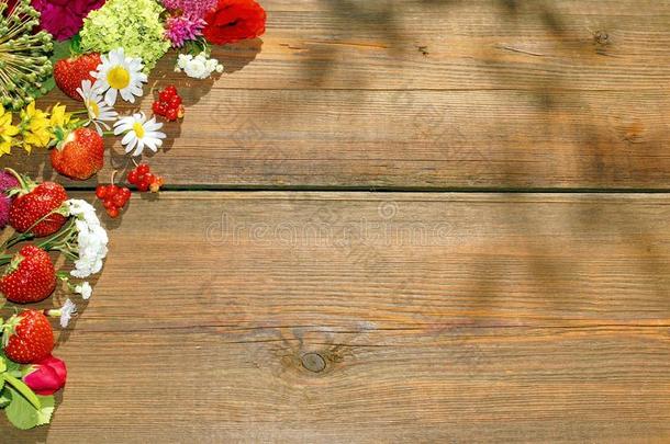 夏天的花朵和浆果放在粗糙的木头桌子上