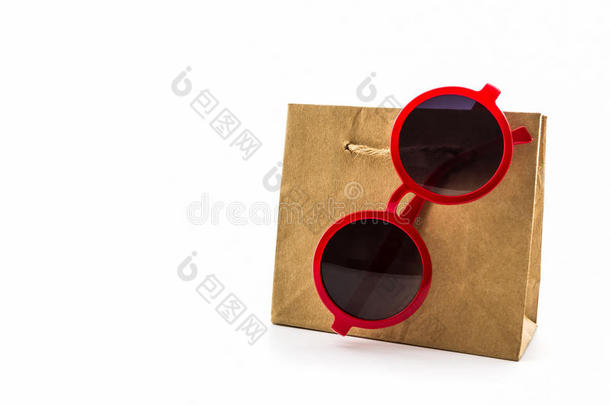棕色购物袋上挂着时尚的红色太阳镜。