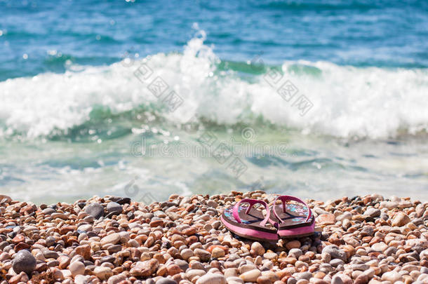 沙滩鞋在海浪中的卵石上