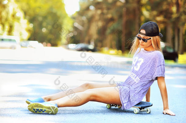 穿着牛仔裤<strong>短腿</strong>的漂亮女孩坐在滑板上