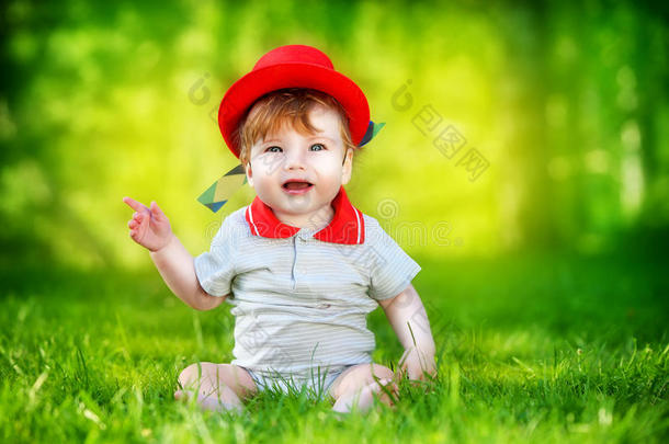 快乐的<strong>小宝宝</strong>戴着红帽子在太阳林的公园里玩得开心。暑假概念。情感。