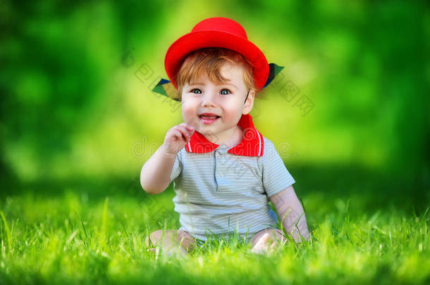 快乐的小<strong>宝宝</strong>戴着红<strong>帽子</strong>在太阳林的公园里玩得开心。暑假概念。情感。