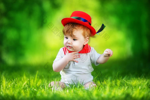 快乐的小<strong>宝宝</strong>戴着红<strong>帽子</strong>在太阳林的公园里玩得开心。暑假概念。情感。