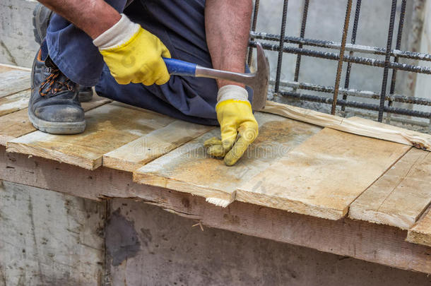 建筑工人用手在木板上钉钉子
