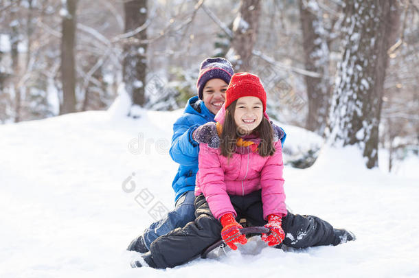 <strong>兄妹</strong>俩坐在公园里的雪橇上。
