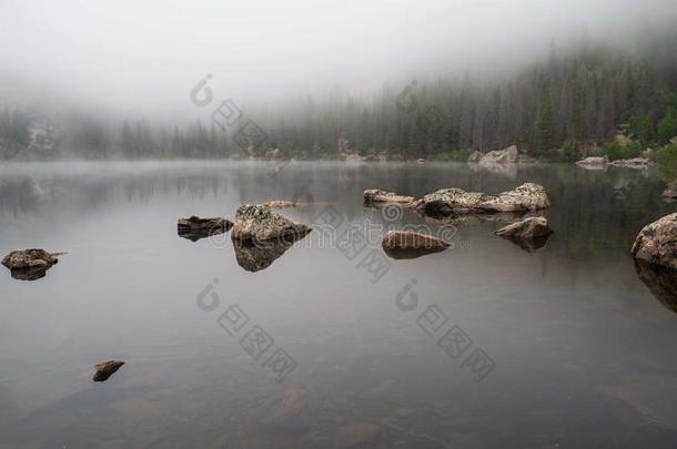 岩石倒映在雾蒙蒙的湖面上