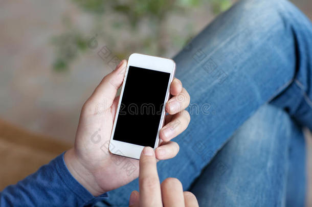 一个男人<strong>坐在沙发</strong>上，手里拿着一个带黑屏的白色触控电话