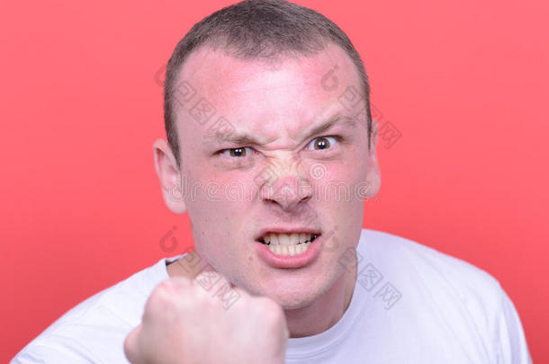 愤怒的男人尖叫的画像在红色背景下露出拳头