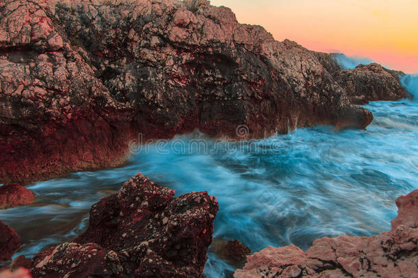 日落时汹涌的海浪拍打着岩石