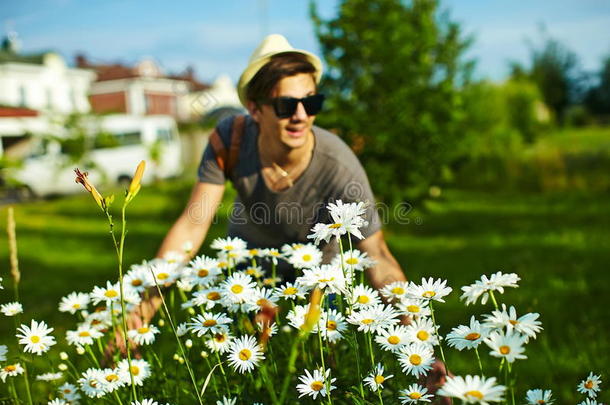 现代时髦的男人穿着休闲的衣服，戴着帽子靠近鲜花