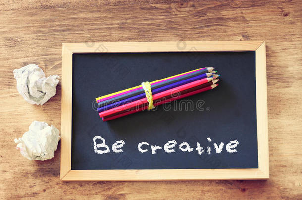 皱巴巴的纸和铅笔堆在黑板上的俯视图，上面写着“要有创意”。