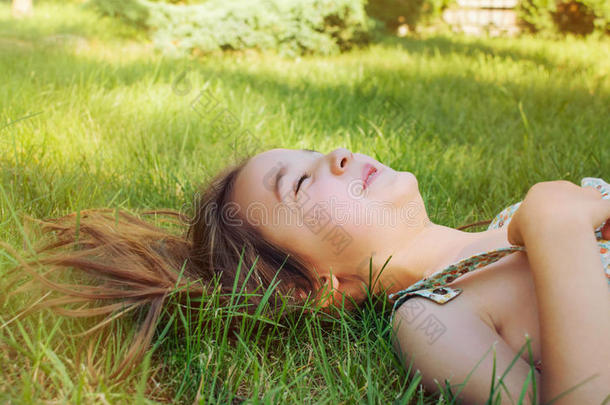 阳光明媚的夏日，快乐的微笑着躺在草地上的小女孩