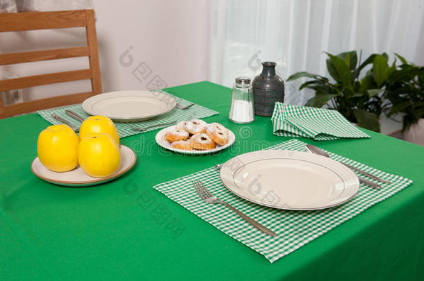 放在桌子上的叉子和勺子放在绿色的布和白色的盘子上