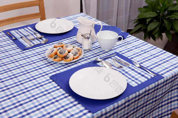 放在桌子上的叉子和勺子放在蓝色的布和白色的盘子上