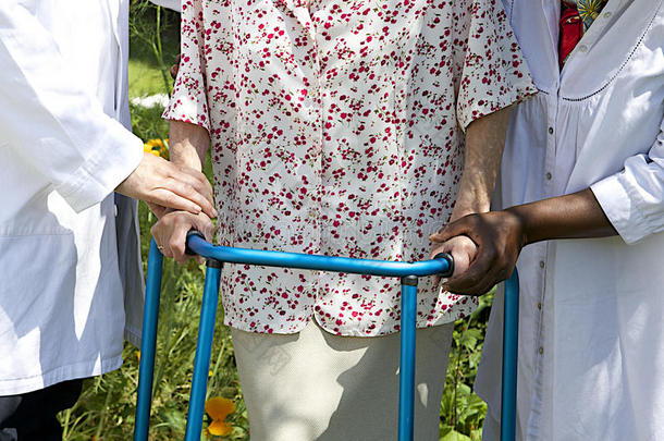 护理人员在室外帮助老年患者使用助行器