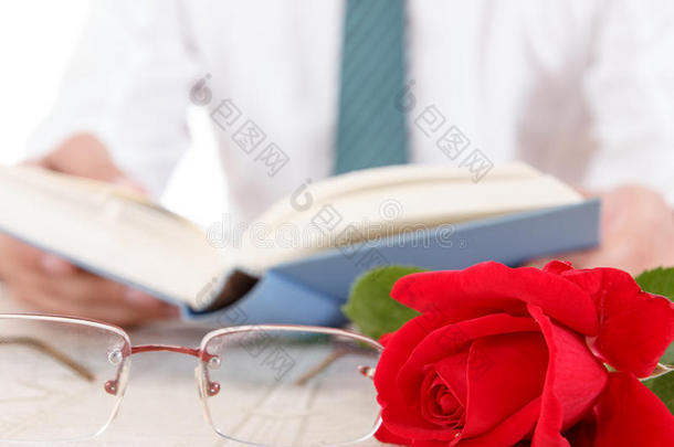 一个穿衬衫打领带的男人，<strong>双手拿</strong>着打开的书，翻阅着书页